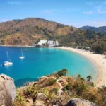 Elevated view over Nai Harn Beach, one of the three Phuket areas compared in the guide